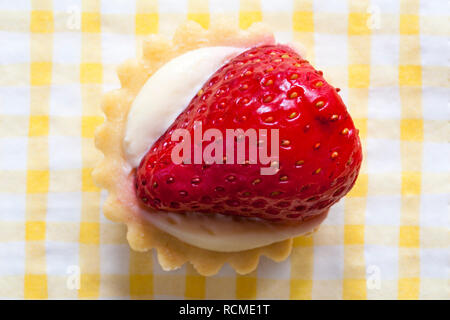 M&S mini fruit tart with strawberry set on yellow and white checked serviette napkin Stock Photo