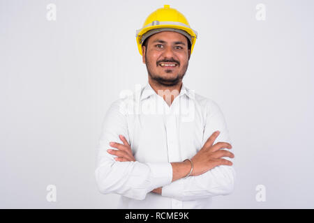 Happy bearded Indian businessman wearing hardhat with arms crossed Stock Photo