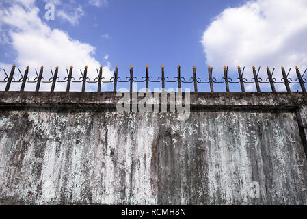 old concrete wall with metal spikes on the top Stock Photo