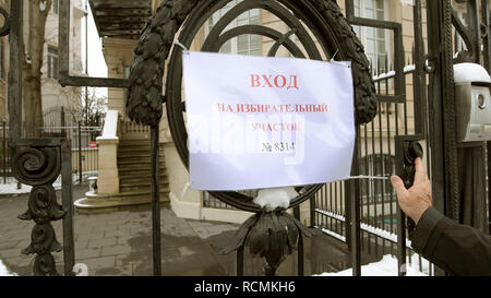 STRASBOURG, FRANCE - MAR 18, 2018: Pooling station text on paper at Russian presidential election 2018 with senior Russian male entering the gate of Consulate General of the Russian Federation to vote for President Stock Photo