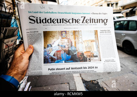 PARIS, FRANCE - MAR 19, 2017: Man reading buying German Sudeutsche Zeitung newspaper at press kiosk featuring Russian presidential election from 2018 and situation in the country with senior woman  Stock Photo