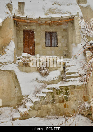 Entrance of historic cave in Cappadocia during a heavy snow fall. Everything covered in pure white snow. Stock Photo