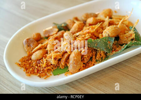 Hot and Spicy Thai Style Roasted Peanuts with Herb Served on Wooden Table Stock Photo