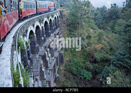 Shimla railway, Train crossing multi arched bridge. Stock Photo