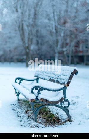 Park bench in snow on cold winter day Stock Photo