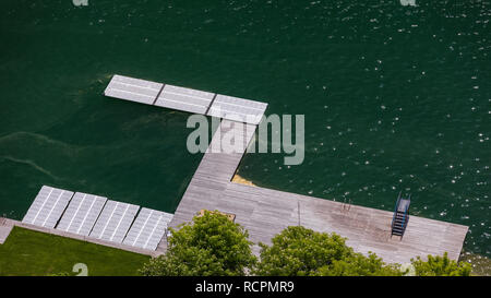 Empty wooden pier close to Bled lake, swimming area of the Bled lake under the sunny sky. Platform beside lake. Wooden pier on the lake. Bled, Sloveni Stock Photo
