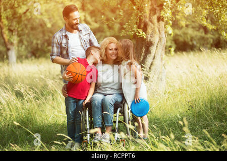 Family portrait. Woman in a wheelchair with her family outdoors. Stock Photo