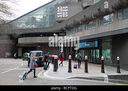 Professional musicians arriving with music instruments at the Barbican Centre entrance in Silk Street London EC2Y  UK  KATHY DEWITT Stock Photo