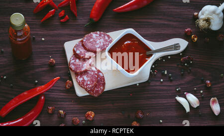 Homemade hot sauce in a white bowl on a wooden background Stock Photo