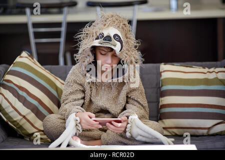 boy in sloth pajamas playing mobile phone Stock Photo