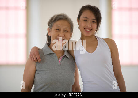 Portrait of a teenage girl hugging her senior grandmother in a yoga studio. Stock Photo