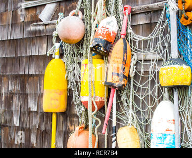 colorful lobster buoys and fishing net hanging on the wall of a weathered fishing shack in Massachusetts Stock Photo