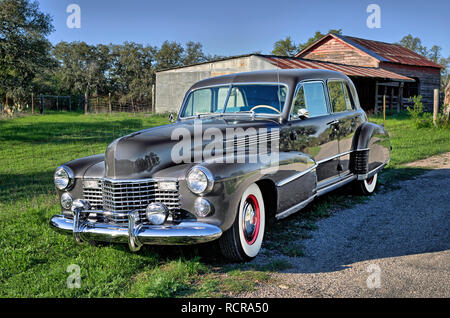 Vintage luxury gray, car with white wall tires and red wheel hubs parked on rural Texas road Stock Photo