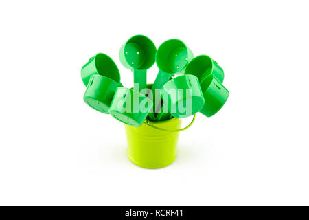 Green plastic spoons in small bucket. Isolated on white background. Stock Photo