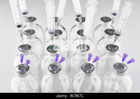 Used medical phials with metal caps. Syringes and needles stuck into bottles. Stock Photo