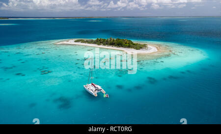 Aerial view of a white catamaran anchored in the clear turquoise waters ...
