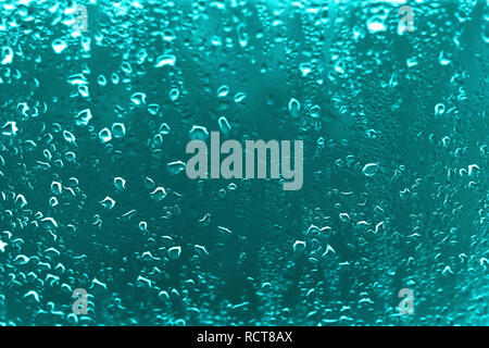 High contrast photo of drops of rain on a window glass with vivid cyan blue color Stock Photo