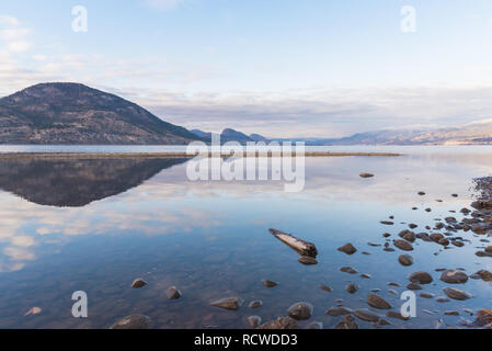 Reflection of clouds and mountains on Okanagan Lake in winter Stock Photo
