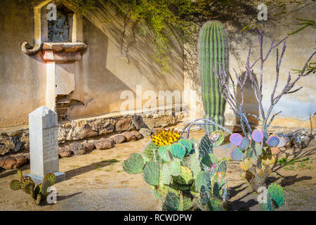 gravestone among cacti in the courtyard At the historical Mission San Xavier del Bac, a Spanish Catholic Mission near Tucson, AZ Stock Photo