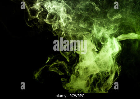Dense multicolored smoke of    green colors on a black isolated background. Background of smoke vape Stock Photo