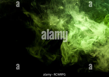 Dense multicolored smoke of    green colors on a black isolated background. Background of smoke vape Stock Photo