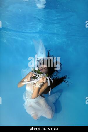 Woman presenting underwater fashion in a pool Stock Photo