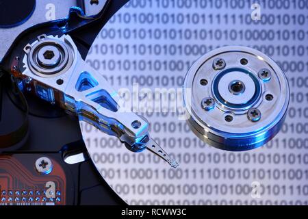 Computer hard drive, opened, read-write head on the disk, binary numbers reflected in the disc, symbolic image Stock Photo