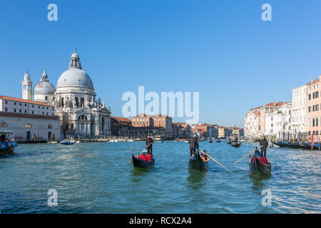 Venice, Italy - March 22, 2018: Gondoliers riding venetian gondolas with a Santa Maria della Salute at background in Venice, Italy Stock Photo