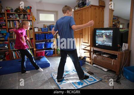 Siblings, a boy, 12 years old, and a girl, 10 years old, playing a dance game on a Wii games console in their room together Stock Photo