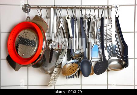 Various kitchen tools and utensils, hanging on a wall in a kitchen Stock Photo