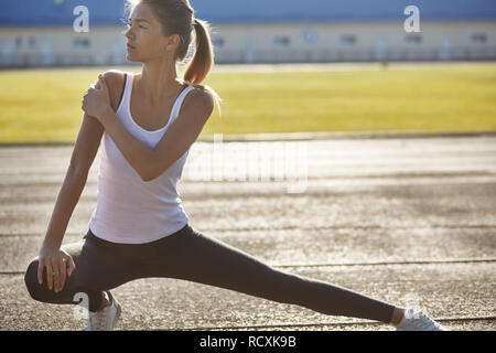 Young runner fit woman streching before exercises outdoors. Athletic female strech after workout outside. Sport and people concept. Stock Photo