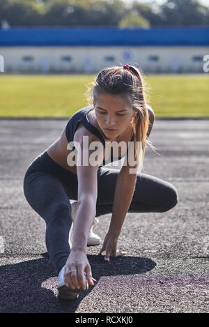 Young runner fit woman streching before exercises outdoors. Athletic female strech after workout outside. Sport and people concept. Stock Photo