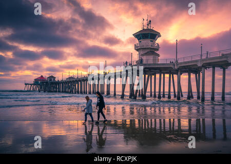 LOS ANGELES, CA/USA - JAN 11, 2019:  People walking along the beach at sunset near Huntington Beach Pier in Los Angeles, California Stock Photo