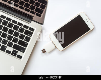 Top view (Flat lay) image of smartphone connected with two way external flash storage and computer (laptop) on white background, Minimalist Stock Photo