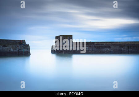 A early morning long exposure of the harbour walls and tower at Craster, just down from Dunstanburgh Castle on the Northumberland Coast. Stock Photo