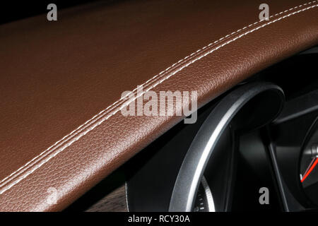 Modern sport car brown leather interior. Part of leather car cockpit details with stitching. Car detailing. Brown perforated leather cockpit. Stock Photo