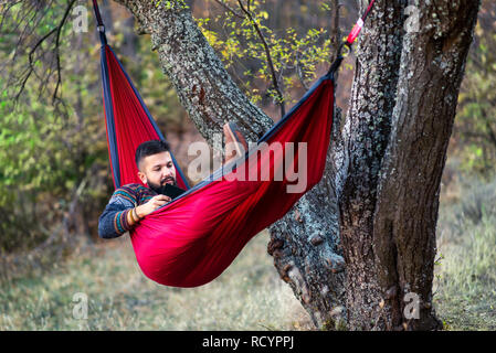 Man reading a book in a hammock and relaxing outdoors