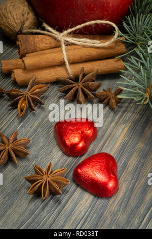 Christmas layout concept on wooden background with bunch of cinnamon anise stars, pine foliage, clementine heart shaped red candies and common walnuts Stock Photo