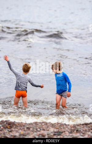 Two boys standing knee deep in the sea having fun, United States