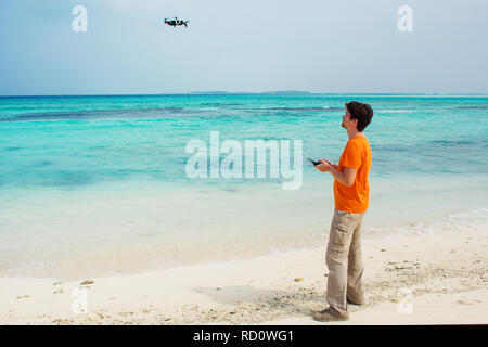 Guy launches a drone over the sea, photo and video shooting on quadrocopter. Drone flights over water, testing. Stock Photo
