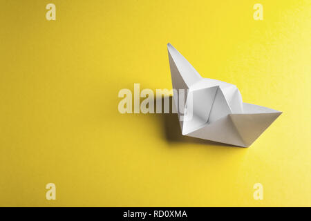Paper boat on a yellow background with copyspace Stock Photo