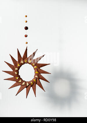 Brown star made of paper hanging in front of a white background, shadow Stock Photo