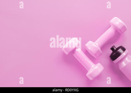 Fitness, Exercise, Working out healthy lifestyle Valentine's day background concept. Pink dumbbells and pink bottle of water on pink background color. Stock Photo