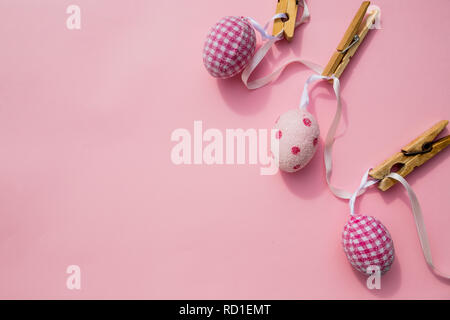 Easter scene with row of hanging colored eggs and pin isolated on pink background. Happy easter composition for spring greeting card.Copy space. Minimalism style. April event holiday concept Stock Photo