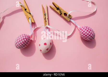 Easter scene with row of hanging colored eggs and pin isolated on pink background. Happy easter composition for spring greeting card.Copy space. Minimalism style. April event holiday concept Stock Photo