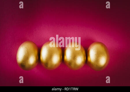 four gold Easter eggs on a purple background Stock Photo