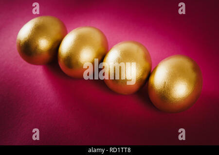 four gold Easter eggs on a purple background Stock Photo