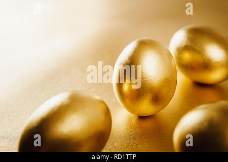 four gold Easter eggs on a shiny background Stock Photo