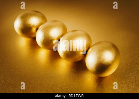 four gold Easter eggs on a shiny background Stock Photo