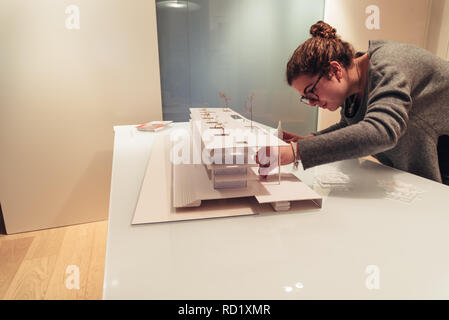 Female architect working on architecture model made with cardboard on table in office of architectural firm Stock Photo